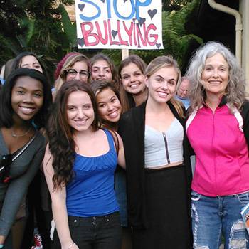 A diverse group of teens holding a stop bullying sign