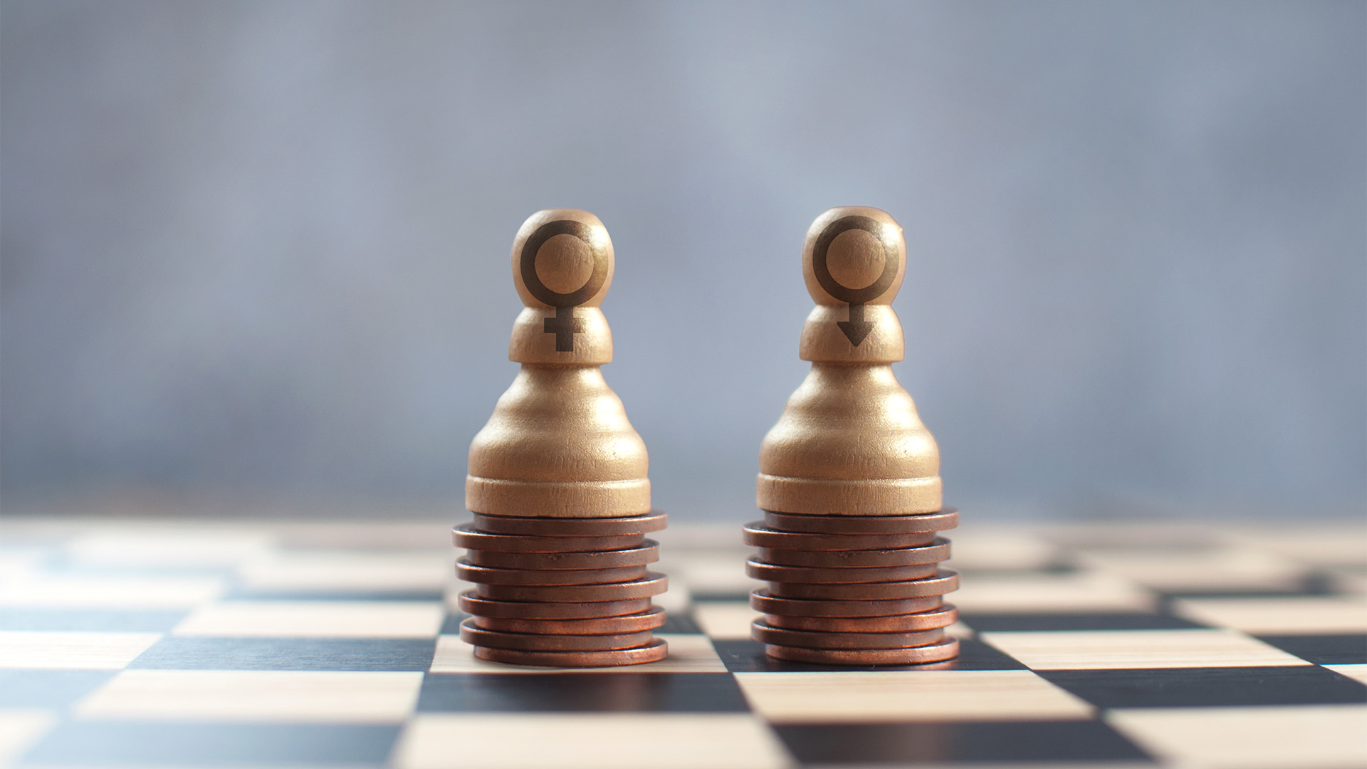 Two pawns on a chess board, one with a female symbol, the other a male symbol with an equal stack of pennies underneath representing pay equity
