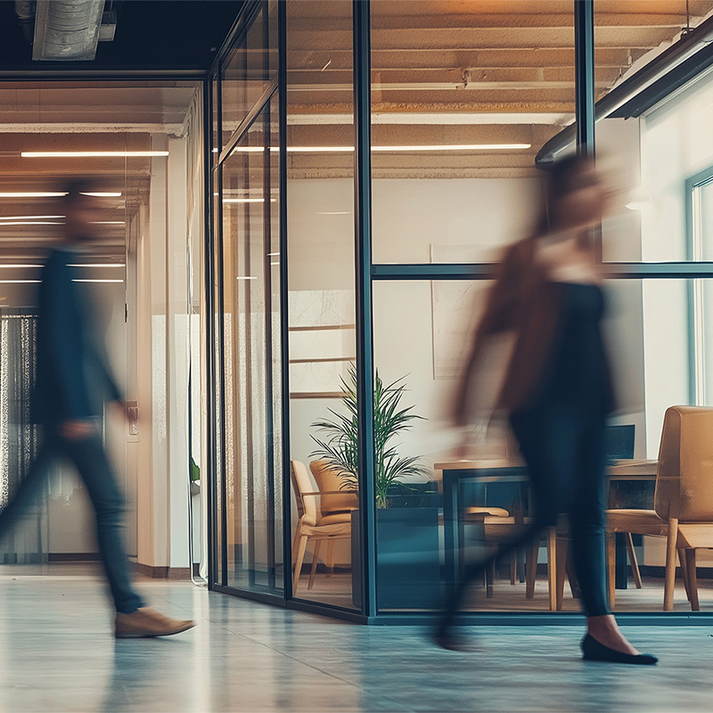 a man and a woman walking quickly out of a building blurred representing attrition in mid-career women in tech