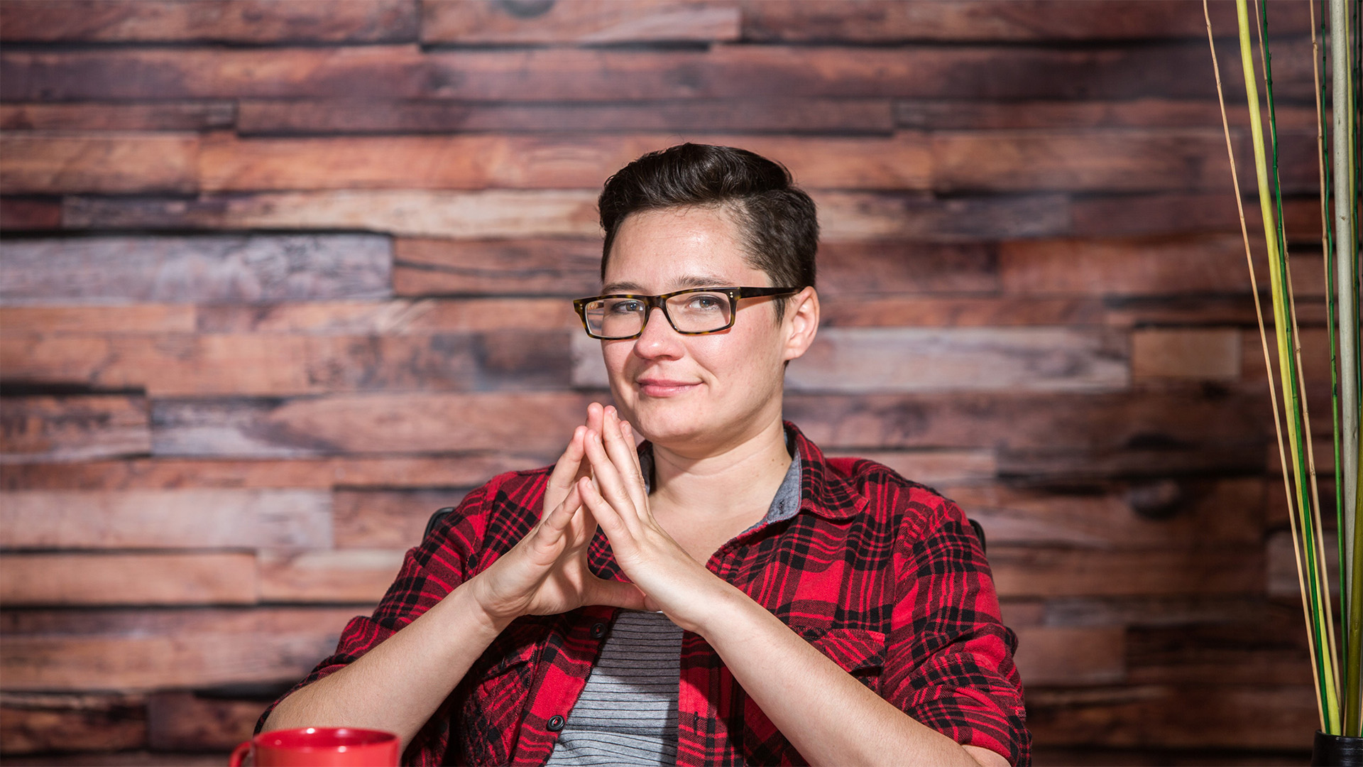 Gay woman in tech with her hands in steeple showing confidence as a leader.